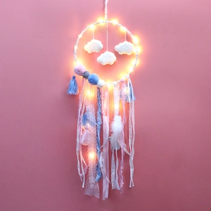 Detail of dream catcher wall decor with cloud charms, colorful pom poms and warm LED lights