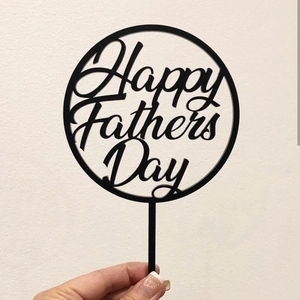 Close-up of black acrylic Happy Father's Day cake topper with creative round cut-out design