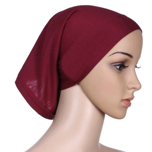 Close-up side view of deep red solid cotton turban cap showing soft stretch fabric texture