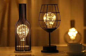 Close-up of wine bottle and glass metal wire lamps with warm LED copper string lights