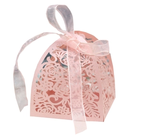 Detail of pink laser-cut wedding favor box with intricate rose patterns and silk ribbon