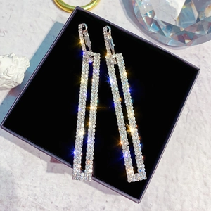 Macro shot of silver-toned rectangular earrings with full rhinestones on jewelry box