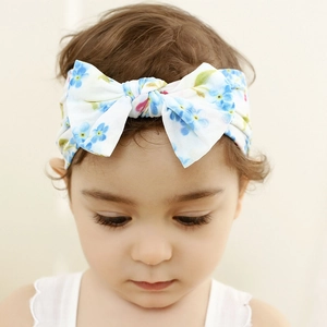 Detailed view of a baby girl wearing a soft nylon headband with blue floral bow design
