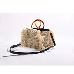 Detail of straw handbag with amber round handle, long tassels and detachable strap