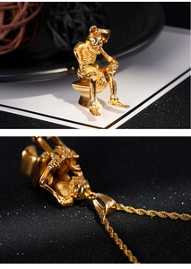 Detailed view of a gold skull thinker on a toilet pendant with a twisted chain