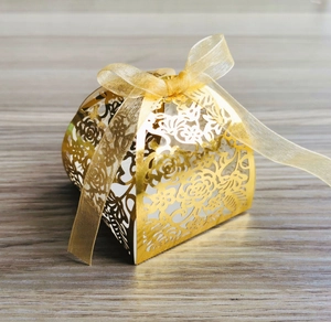 Close-up of golden hollow flower candy box with laser-cut patterns and a silk ribbon bow