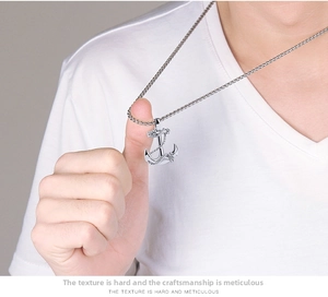 Gros plan d'un pendentif ancre en argent avec détails de corde sur une chaîne tressée