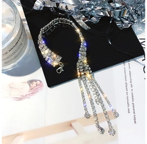 Détail macro d'un bracelet à pompons en strass argenté avec fermoir mousqueton sur velours noir