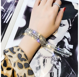 Détail d'un ensemble bracelet à pompon en cristal argenté et bague sertie de strass multicouches