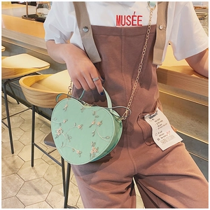 Detail of heart-shaped crossbody bag with floral lace embroidery and gold chain strap