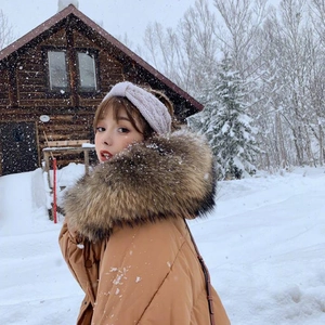Winter outfit detail with camel down jacket, large fur hood and white knit headband