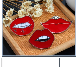 Detailed view of three red enamel lip brooches with white teeth on a rustic woven tray
