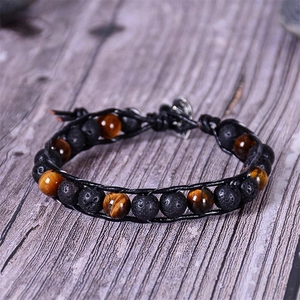 Detail of tiger eye and lava stone beads with braided leather strap on wood