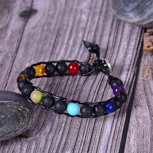 Close-up of lava stone and tiger eye beads with leather cord on a wood background