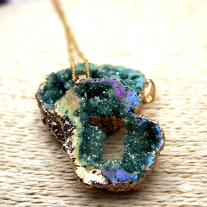 Detalle del colgante de geoda de ágata natural con cristales y baño de oro