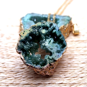 Primer plano macro de colgante de geoda de ágata verde con bordes chapados en oro fino