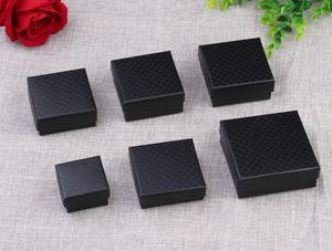 Multiple sizes of black diamond textured jewelry gift boxes arranged with a red rose