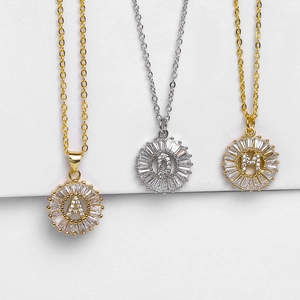 Dettaglio di collane a girasole con lettere in zirconi in finiture oro e argento