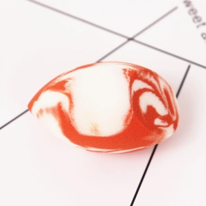 Detailansicht vom Make-up-Schwamm mit orange-weißem Marmormuster in Tropfenform