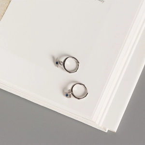 Detail of S925 silver evil eye hoop earrings with blue stone and zircons on a book