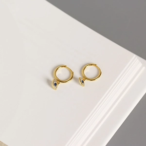 Close-up of gold S925 sterling silver evil eye hoop earrings with blue crystal detail