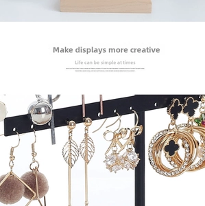 Detail of assorted dangling earrings on a black T-bar display stand with various charms