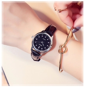 Detail of elegant black leather strap watch with silver case worn on woman wrist