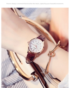 Close-up of women's quartz watch with rose gold case and burgundy leather strap