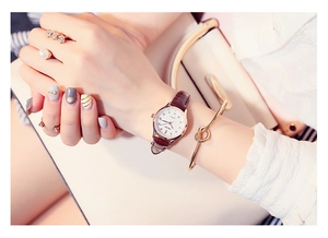Close-up of a women's quartz watch with brown leather strap and gold rhinestone dial