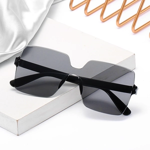 Chic oversized square rimless sunglasses with dark lenses on a luxury display stand