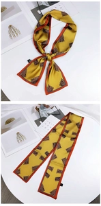 Detail of yellow silk twilly scarf with orange edges and abstract brown prints