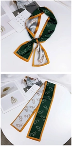 Detail of green silk scarf with abstract face lines and orange border on white table