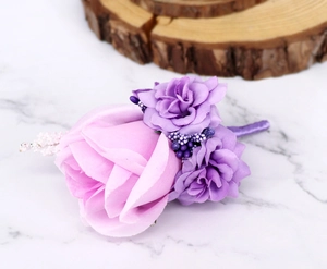 Detailed close-up of a purple silk rose boutonniere with ribbon-wrapped stem