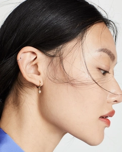 Detail of gold star pendant earring with sparkling zircon and minimalist cartilage cuff