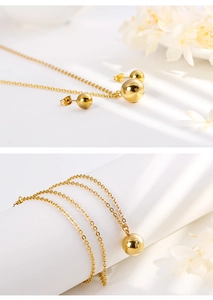 Close-up of golden spherical pendant necklace and ball stud earrings jewelry set