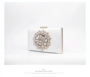 Detail of white satin evening clutch with sparkling rhinestone flower and gold clasp