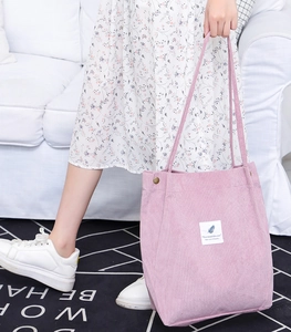 Close-up of pink corduroy tote bag with fabric label and metal side buckle detail