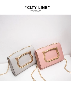 Detail view of pink and grey crossbody bags with gold cat-shaped metal hardware