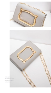 Detail of grey PU leather bag with golden cat-shaped metal handle and chain strap