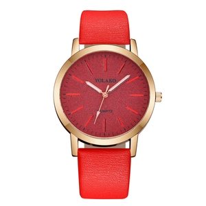 Close-up of the red matte texture dial and gold watch case on a minimalist leather strap
