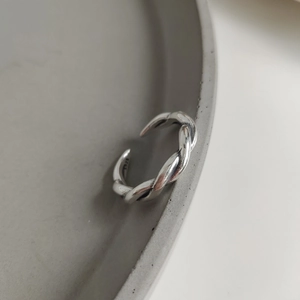 Detailed close-up of woven S925 sterling silver twist ring on a ceramic tray