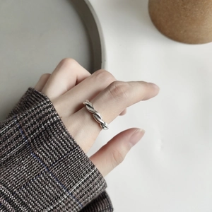 Close-up of minimalist 925 sterling silver woven ring worn on a finger