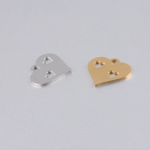 Close-up of gold and silver hollowed heart pendants in mirror stainless steel