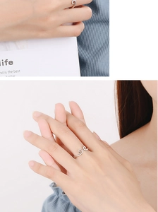 Detail of silver wavy open ring shown on a model hand with minimalist aesthetic