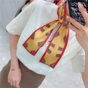 Detail of yellow silk scarf with red edges worn as a stylish wristband accessory