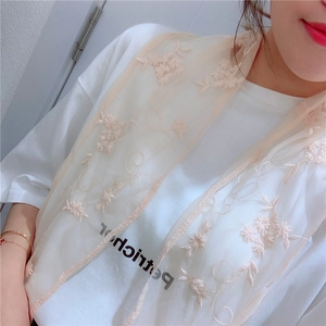 Detail of beige sheer lace scarf with delicate floral embroidery and wavy edges