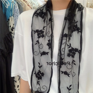 Detail of black transparent lace scarf featuring delicate floral embroidery on wave edge