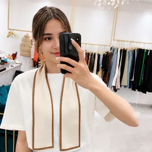 Mirror selfie showing a cream long silk scarf with orange and black chain prints