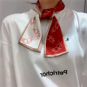 Detailed view of long silk scarf with red abstract print tied as stylish wristband