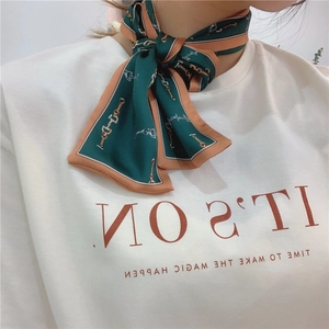 Close-up of elegant forest green silk scarf with horsebit chain pattern around the neck